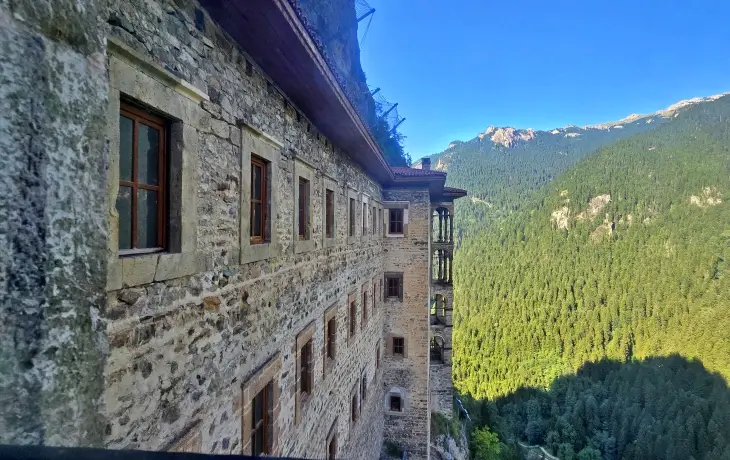 Sümela Manastırı’nın çok katlı keşiş hücreleri ve taş cephe duvarları, dik yamacın üzerindeki konumu ve Altındere Vadisi’nin yeşil orman manzarasıyla birlikte görünüm.